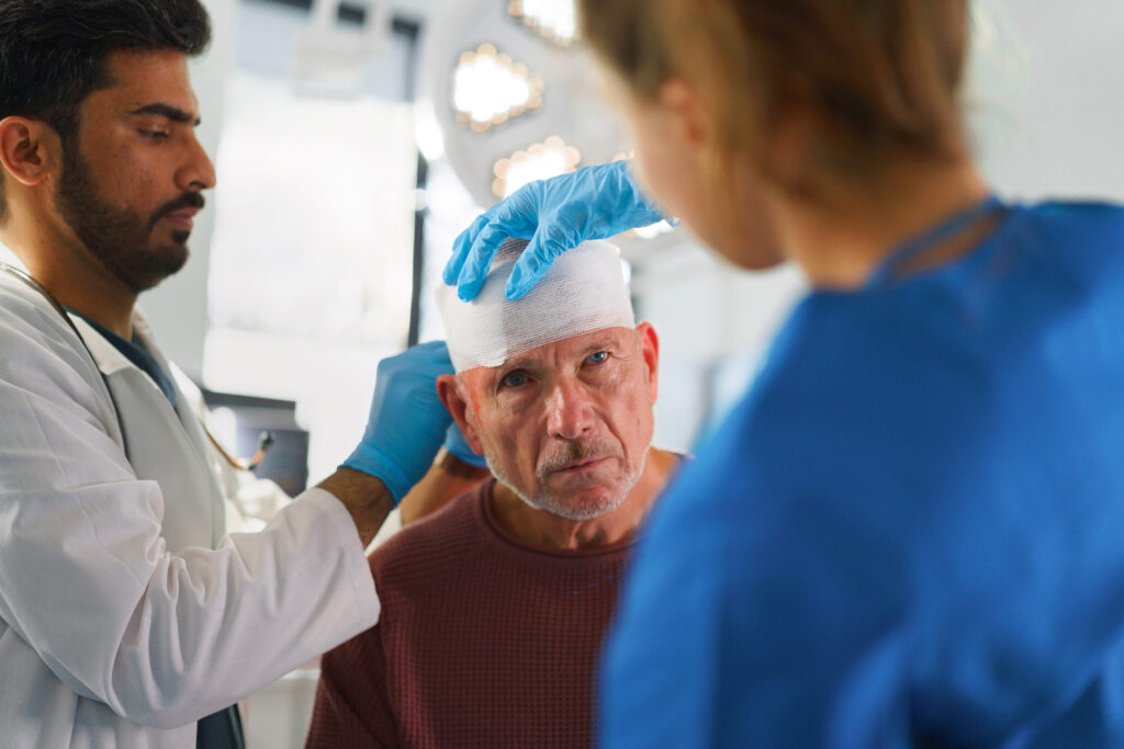 Medical professionals applying a bandage to a patient’s head injury in a clinical setting.