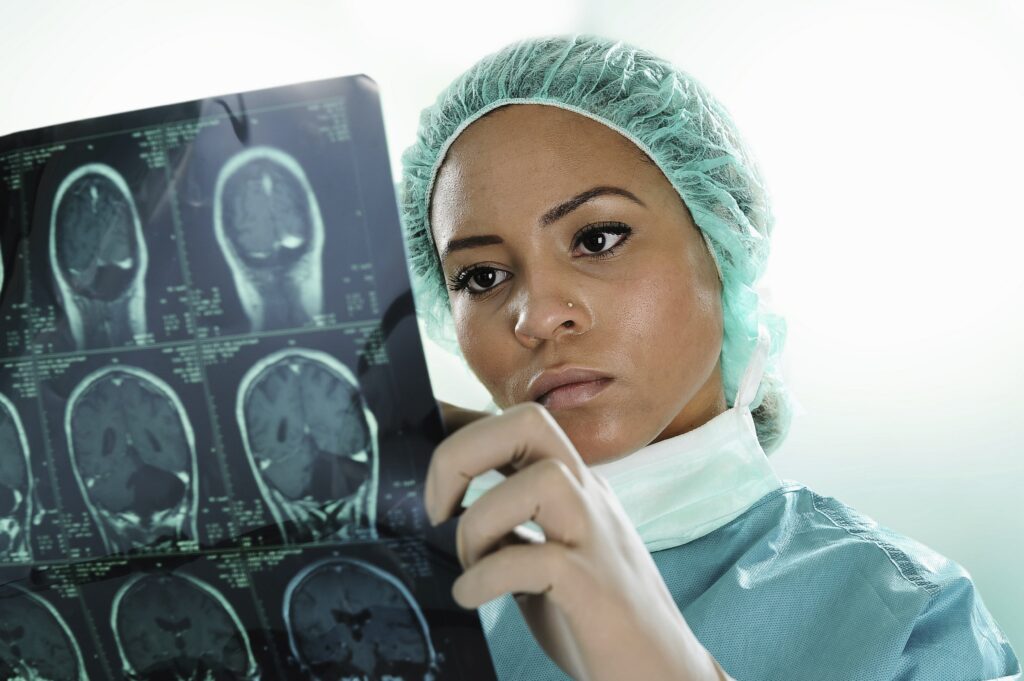 Healthcare professional in surgical attire examining brain MRI films for neurological assessment.